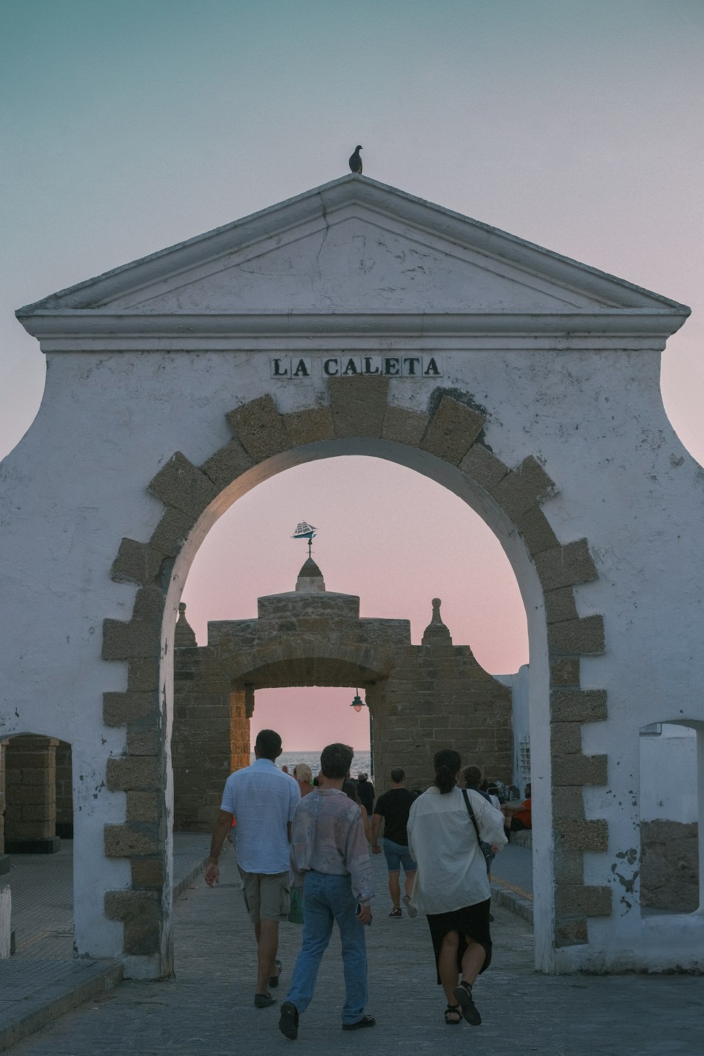 a group of people walking through a stone archway