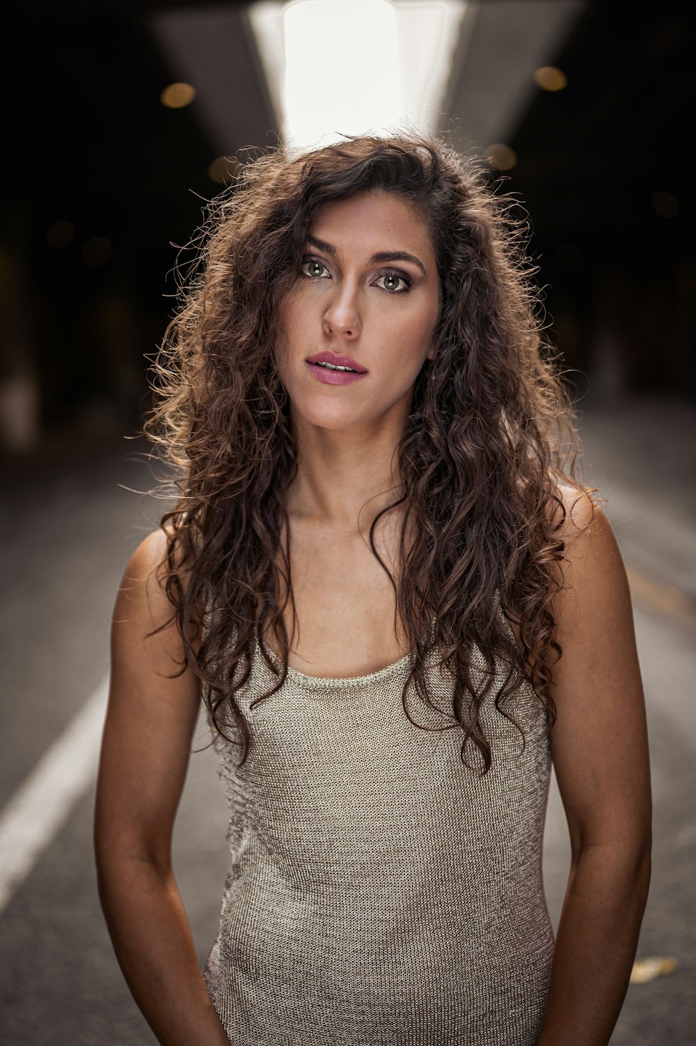 a woman with long hair standing in a tunnel