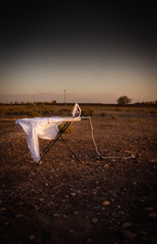a white sheet on top of a chair in the middle of a field
