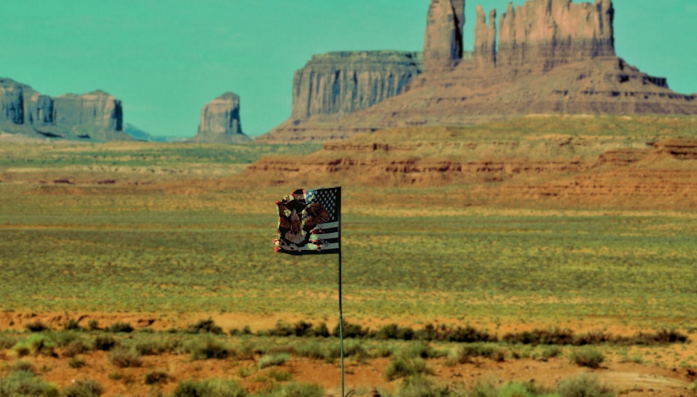 a flag in the middle of a desert with mountains in the background