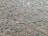 A surface that appears to be a cobblestone path with various shapes and sizes of stones embedded in the ground. The stones are mostly irregular, some of them slightly polished, and are set in a mix of sandy and earthy material.