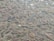 A surface that appears to be a cobblestone path with various shapes and sizes of stones embedded in the ground. The stones are mostly irregular, some of them slightly polished, and are set in a mix of sandy and earthy material.