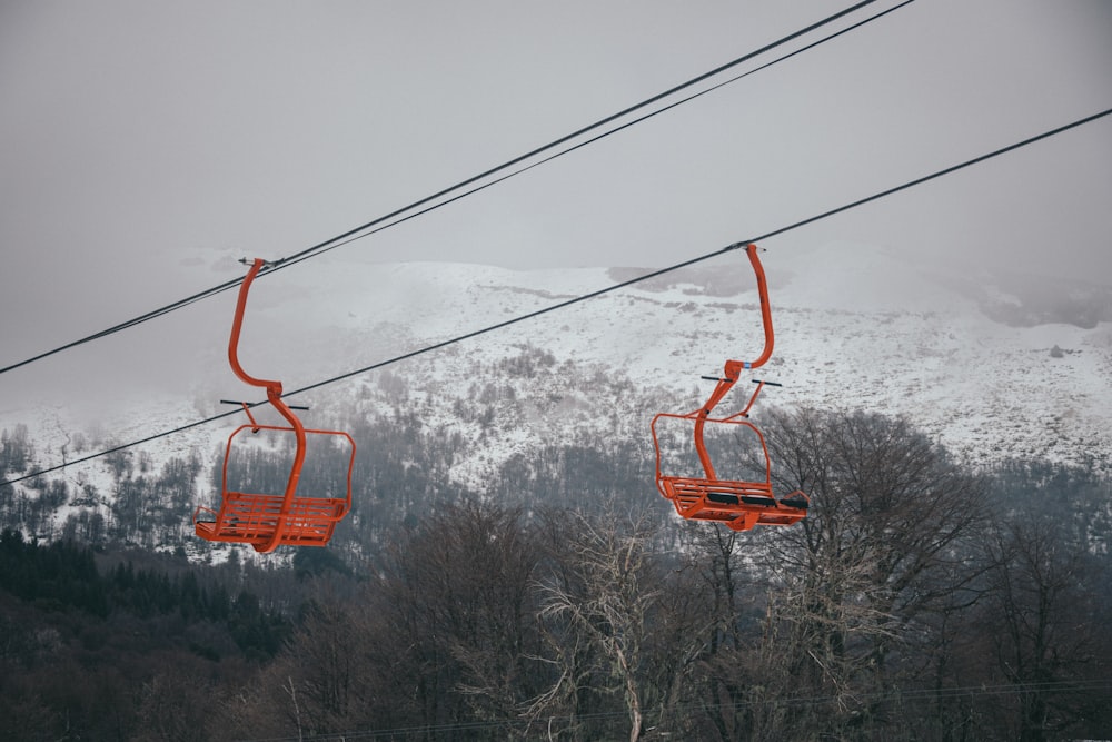 Un par de sillas naranjas sentadas en la cima de una pista de esquí