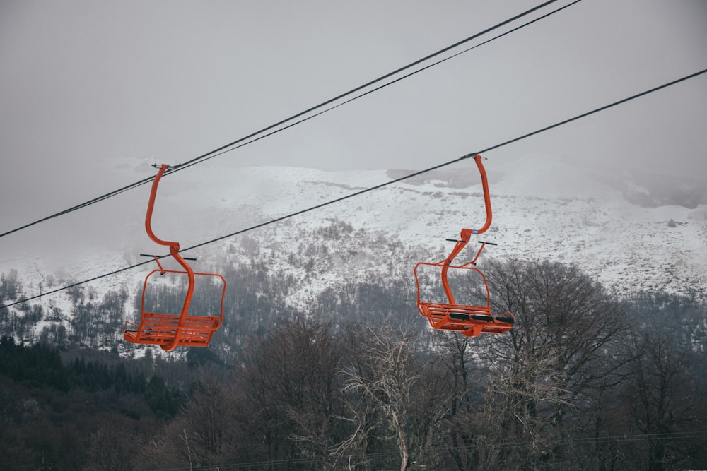 a couple of orange chairs sitting on top of a ski slope