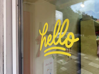 Bright window decals featuring colorful vinyl lettering on a glass pane.