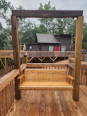 A rustic wooden swing hanging from a large tree with a view of the cabins.