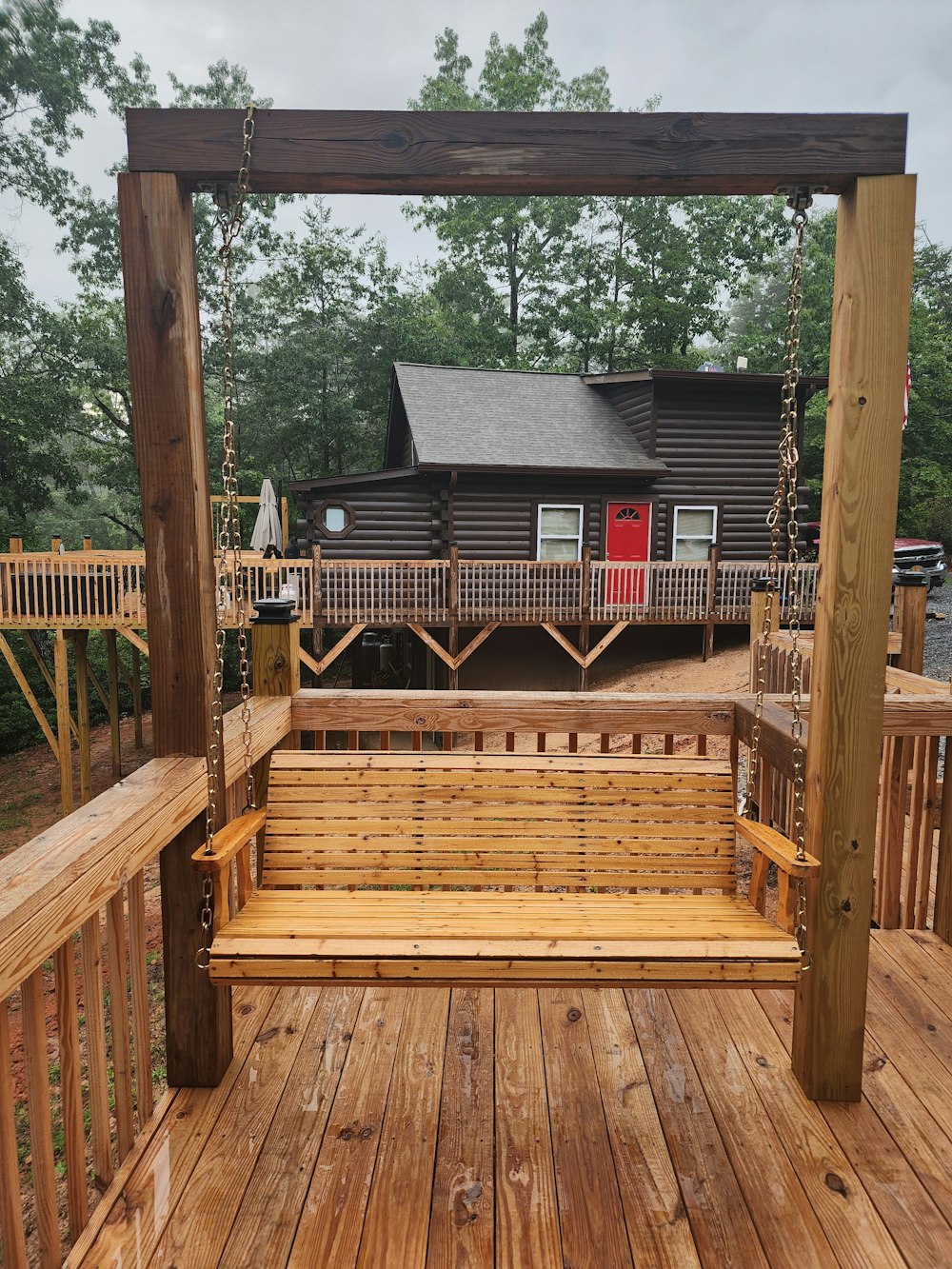 a wooden porch with a swing and a house in the background