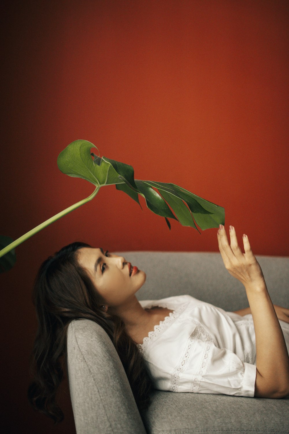 a woman laying on a couch holding a green plant
