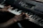 Close-up of hands expertly playing a vintage keyboard in a dimly lit studio.