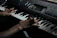 Close-up of hands expertly playing a vintage keyboard in a dimly lit studio.