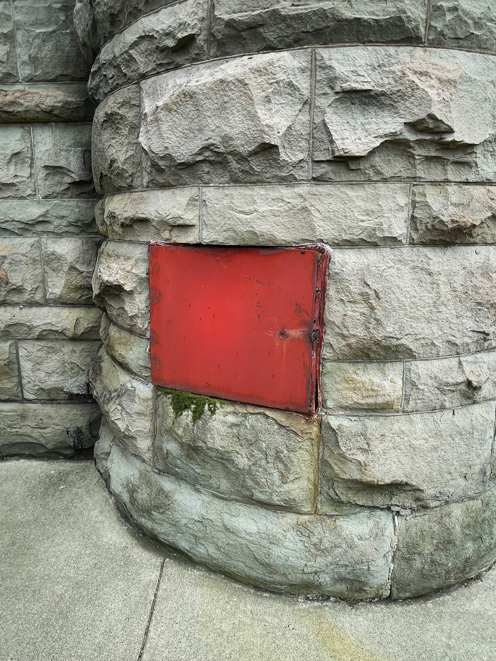 Un letrero rojo está en una pared de piedra