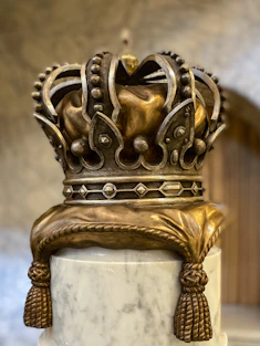 a gold crown on top of a marble pedestal
