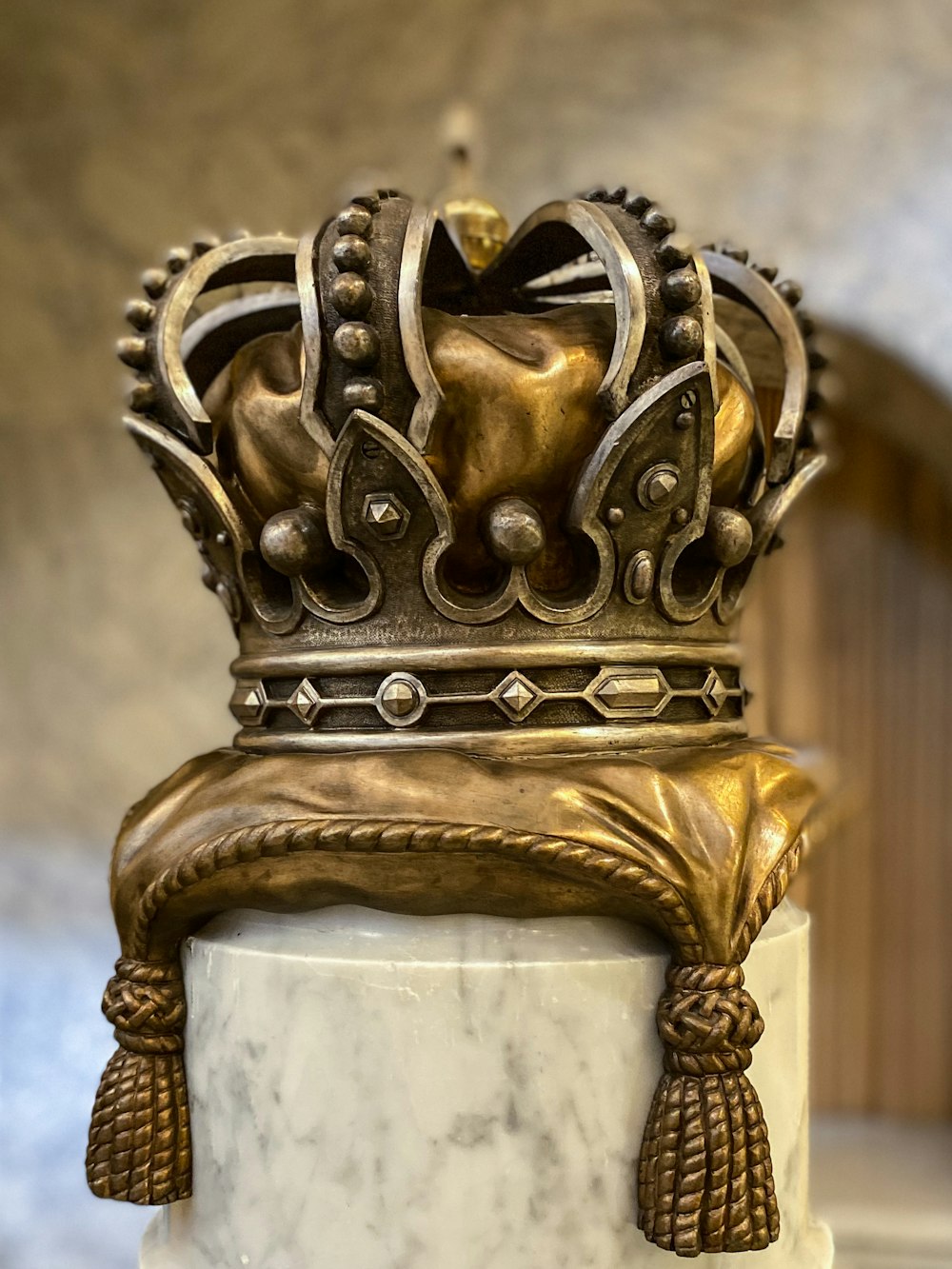 a gold crown on top of a marble pedestal