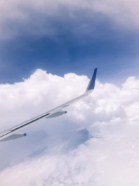 Rocket cruising mid-air above a blanket of fluffy white clouds under clear sunlight.