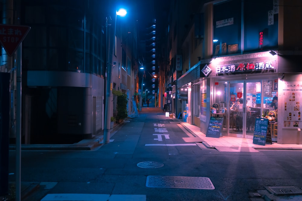 a city street at night with a store front lit up