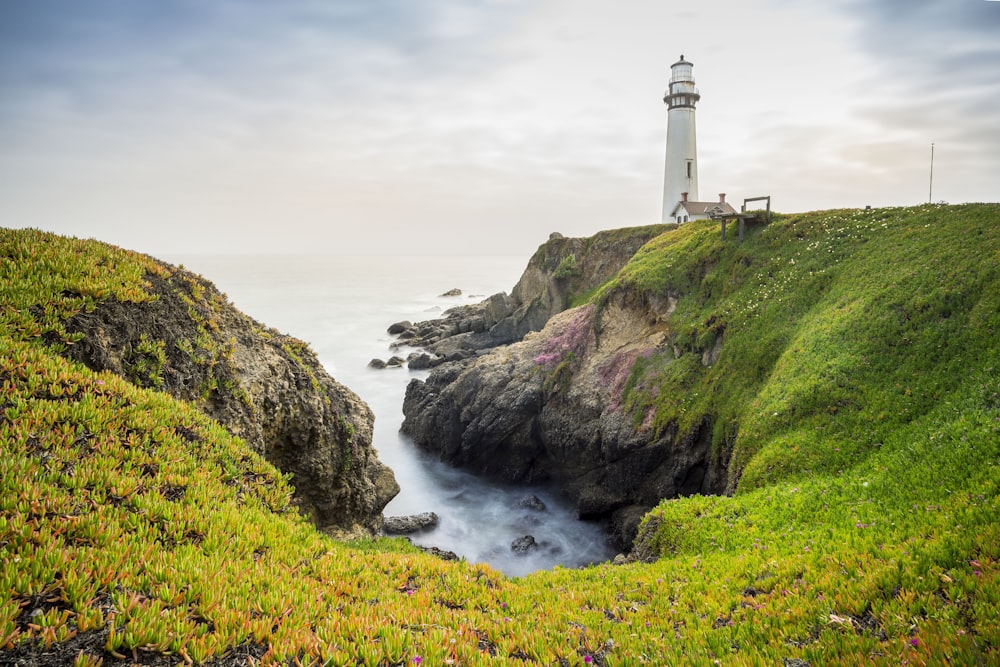 a lighthouse on top of a cliff next to a body of water