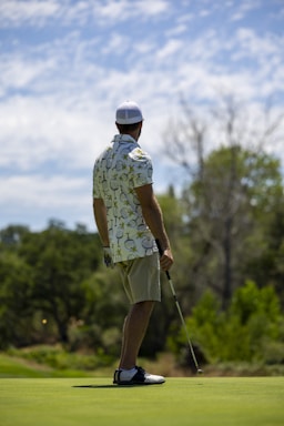 A friendly golf instructor smiling while holding a golf club on a sunny course.