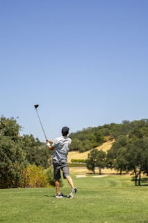 A golfer taking a powerful swing on a sunny driving range.