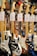 A collection of electric guitars with various colors and designs, neatly displayed in a music store. Each guitar has a label displaying its model and price.