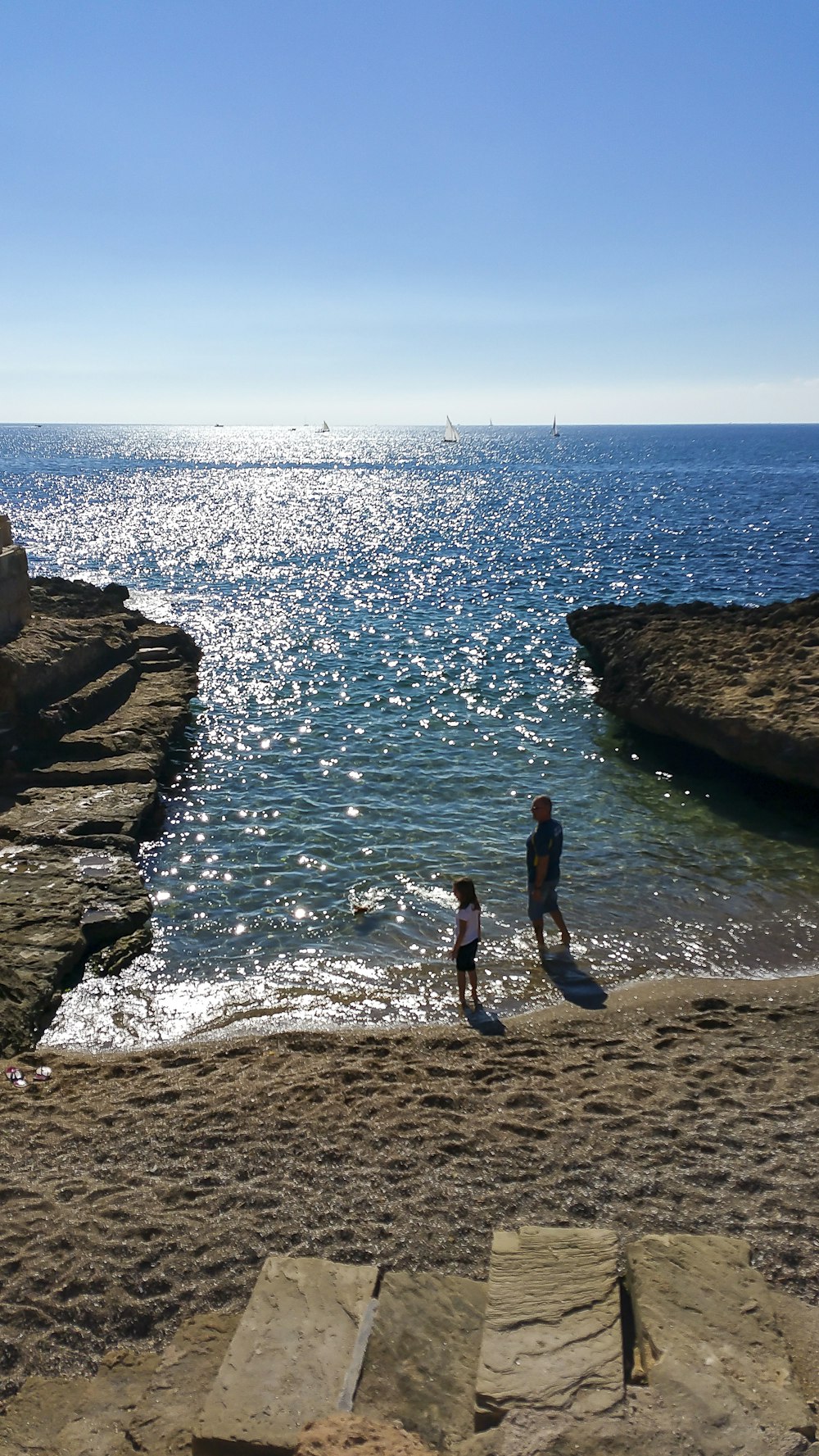 a couple of people standing on top of a sandy beach