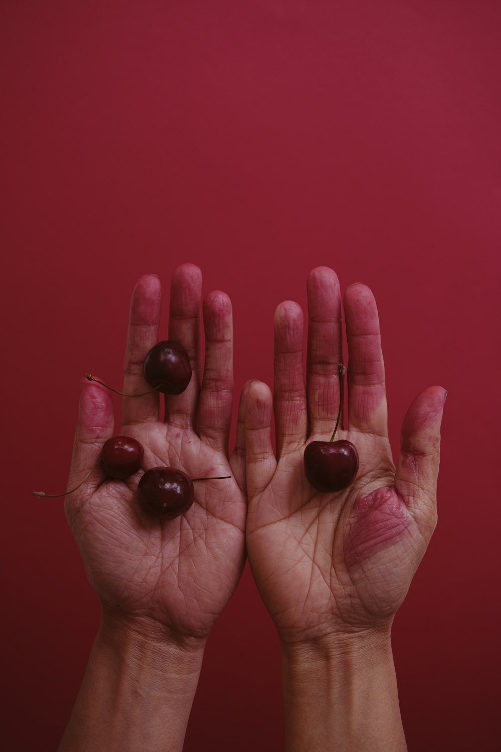 a person holding two cherries in their hands