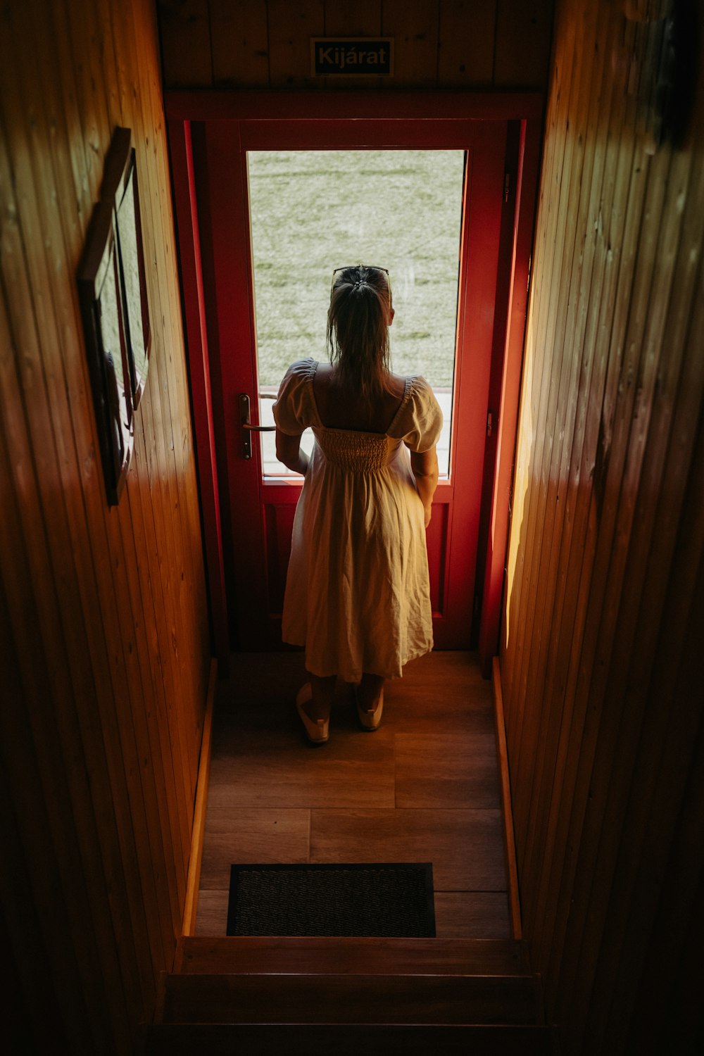 a little girl in a yellow dress looking out a window