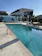 A guest relaxing by the modern hotel pool under a clear blue sky.