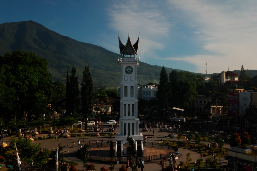 a large white clock tower sitting in the middle of a park