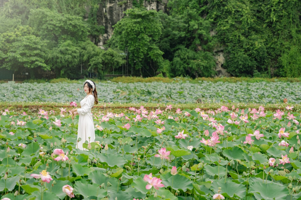 a woman in a white dress standing in a field of flowers