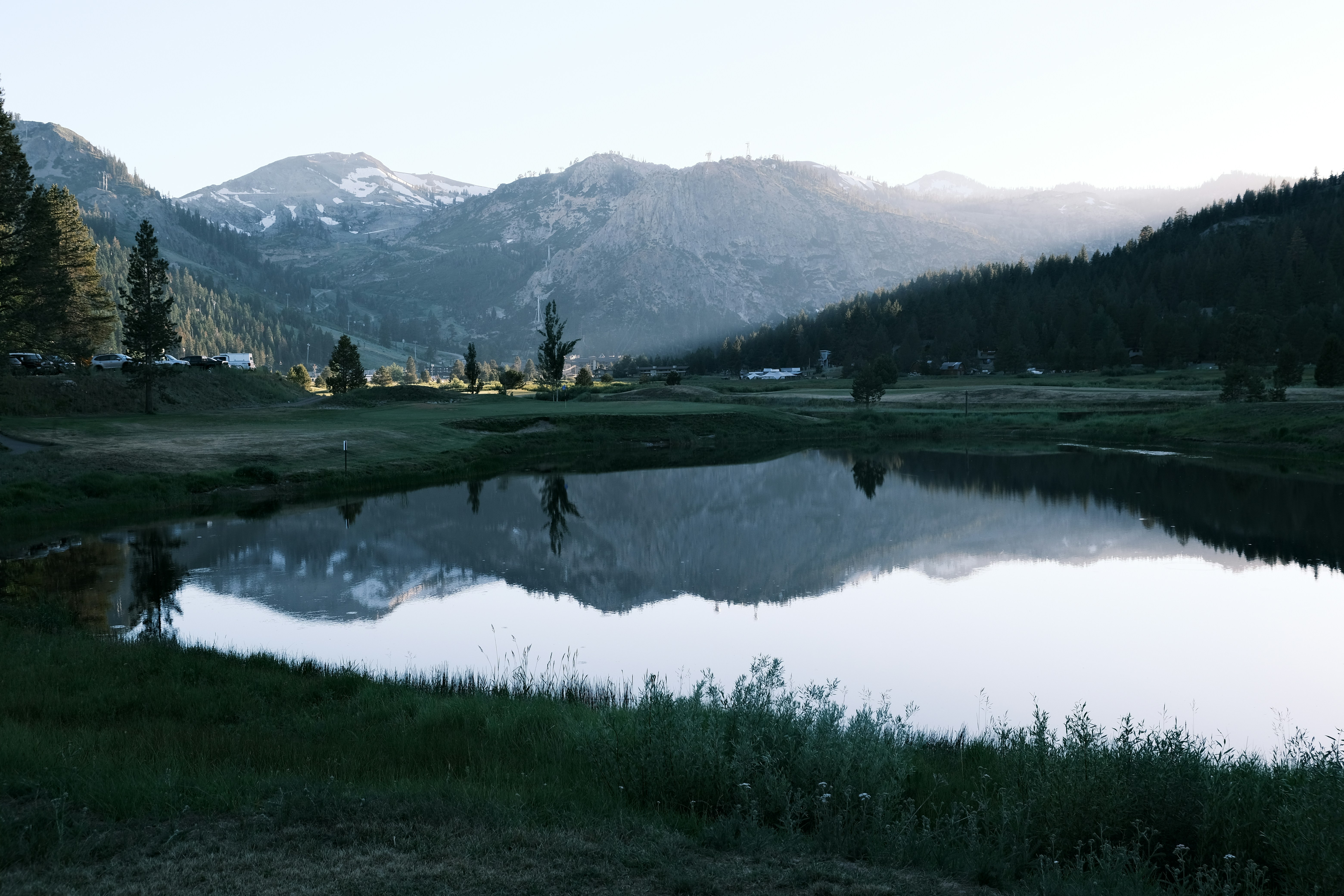 a small lake surrounded by mountains and grass