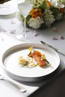 A clean white plate showcasing a beautifully plated salmon dish with a navy blue napkin beside it