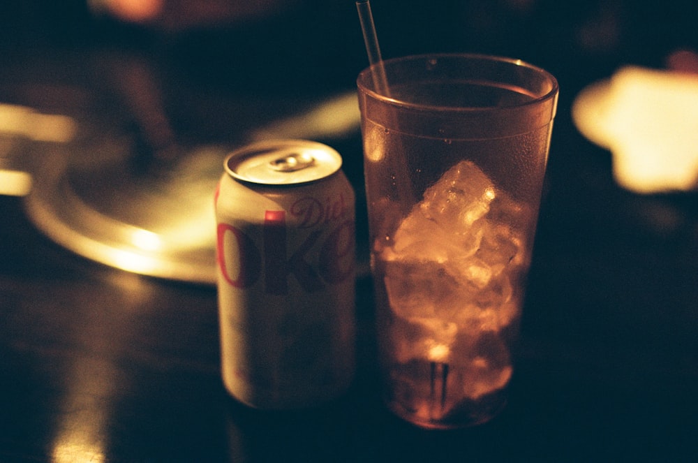 a can of soda and a glass on a table