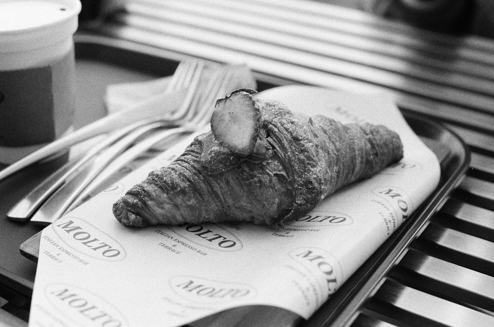 a piece of bread sitting on top of a table next to a cup of coffee