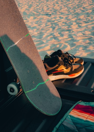 A close-up of colorful sneakers on a skateboard resting on a sunny sidewalk.