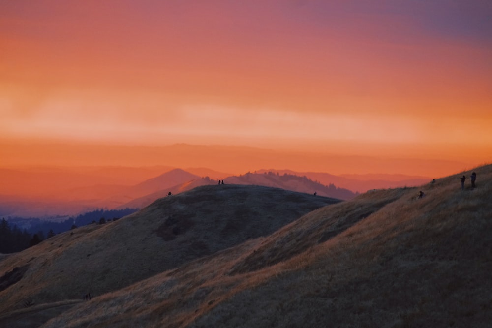 a group of people walking up a hill at sunset