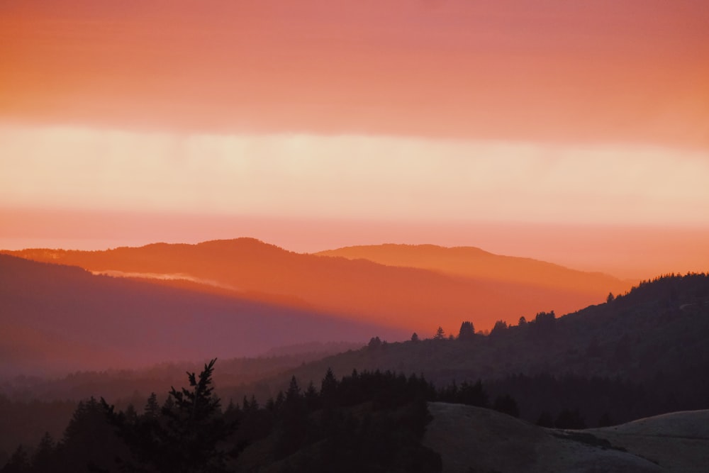 the sun is setting over a mountain range