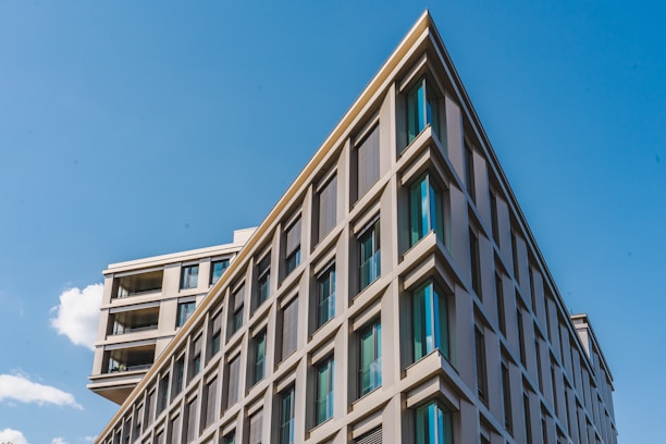 Modern mid-rise residential building with clean lines under a clear blue sky.