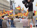 Venezuelan citizens watching news coverage on their smartphones in a public square.
