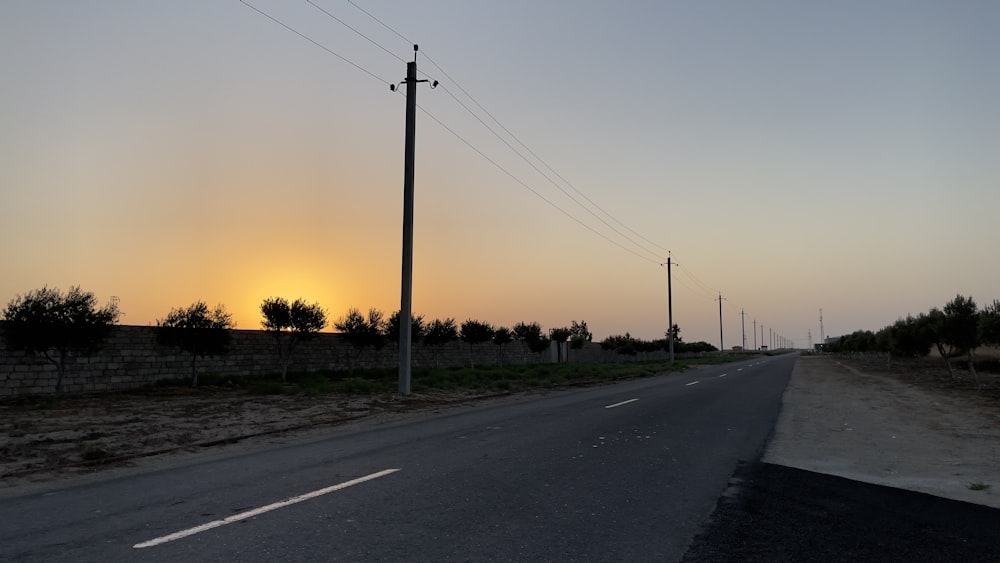 the sun is setting over a rural road