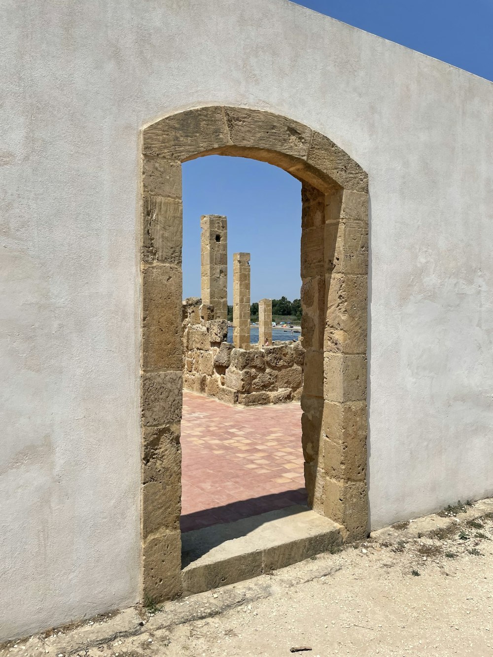 a stone arch with a brick walkway leading to a body of water