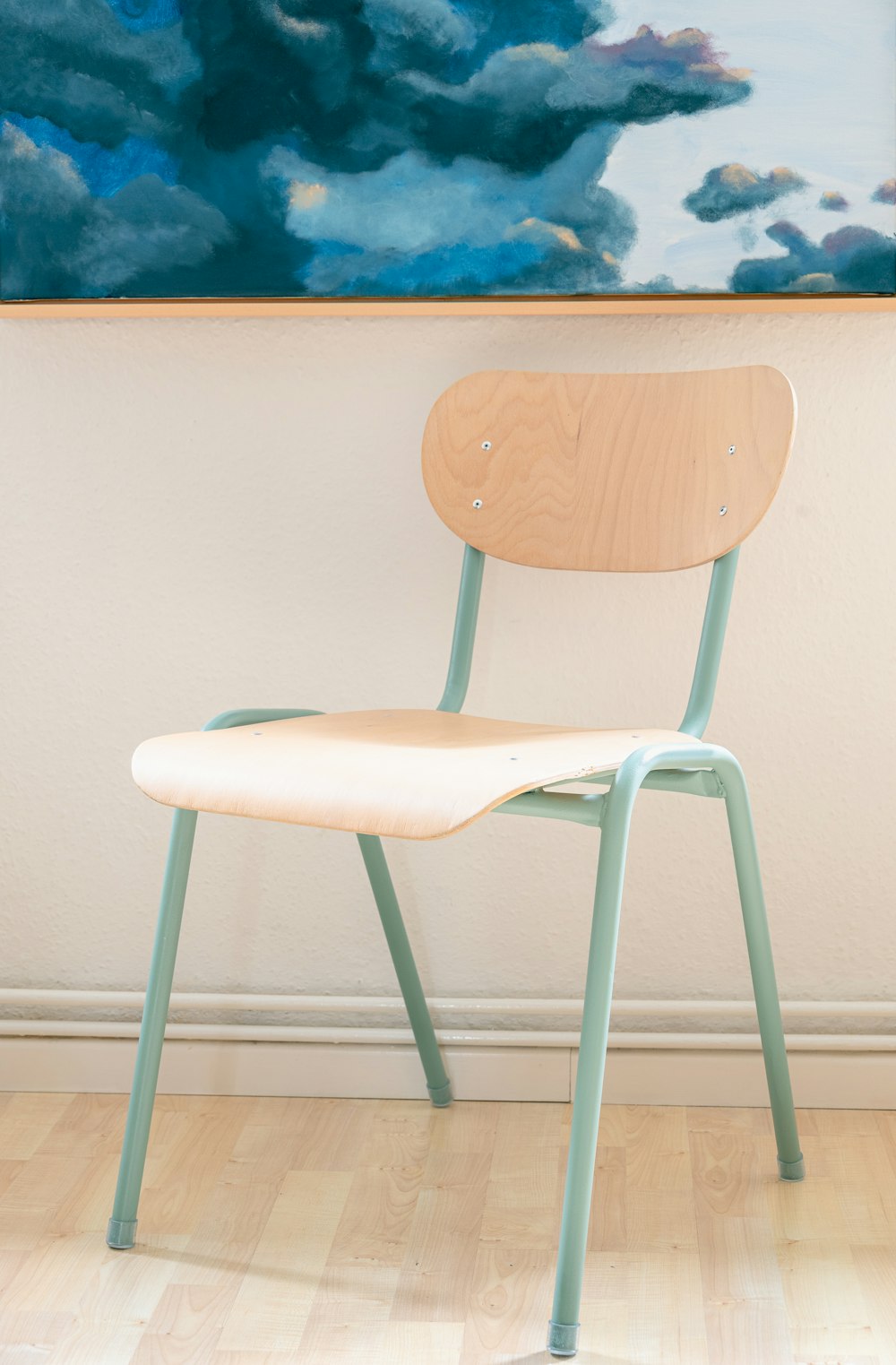 a wooden chair sitting in front of a painting