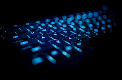 Close-up of a sleek laptop keyboard glowing with blue backlight.