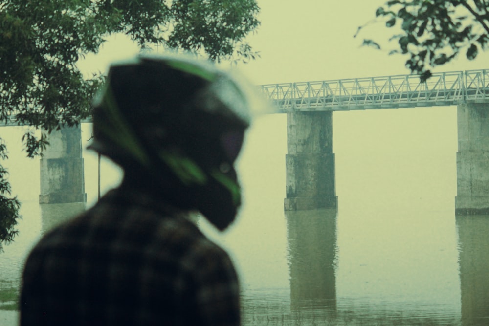 a man standing in front of a bridge on a foggy day