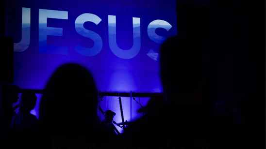 A warm, inviting photo of Jesús speaking passionately in front of a softly lit background with subtle biblical symbols.