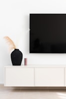 Minimalist black and beige TV console with integrated lighting and decorative items.