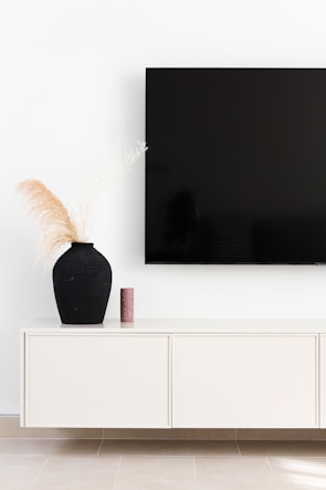 Minimalist black and beige TV console with integrated lighting and decorative items.