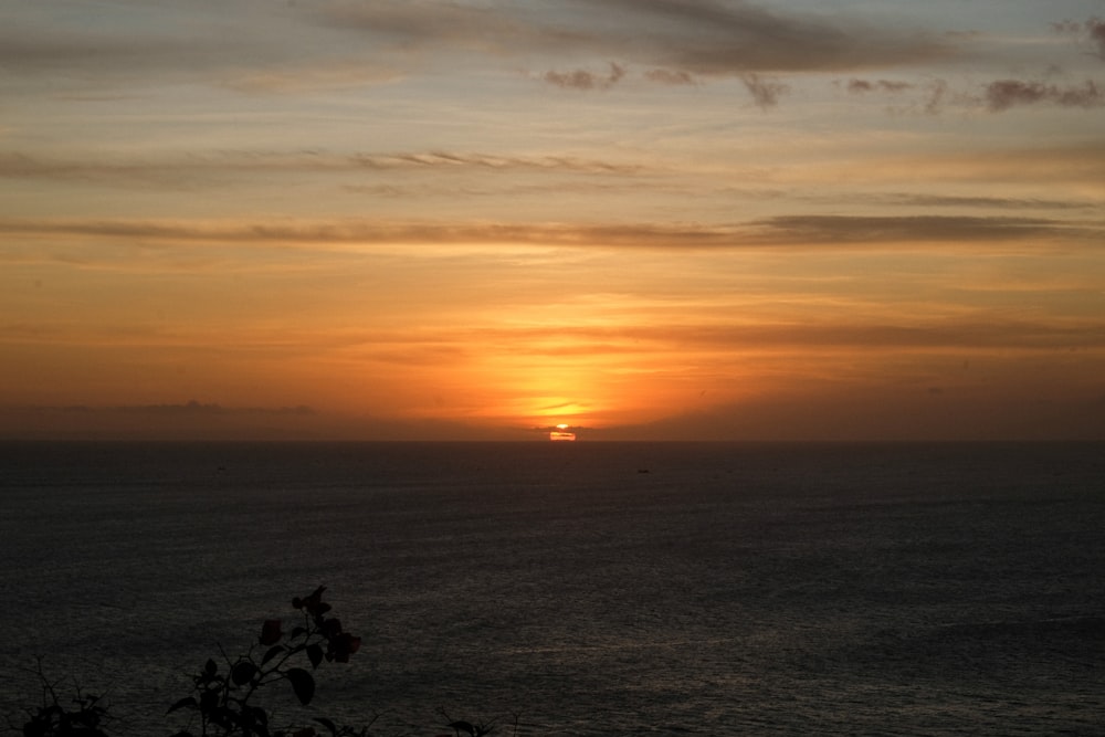 the sun is setting over the ocean on a cloudy day