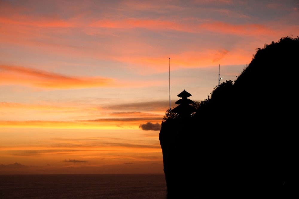 a person standing on a cliff with a sunset in the background