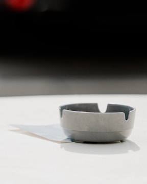 Close-up of a black 3D printed ashtray with sleek urban design on a concrete surface.