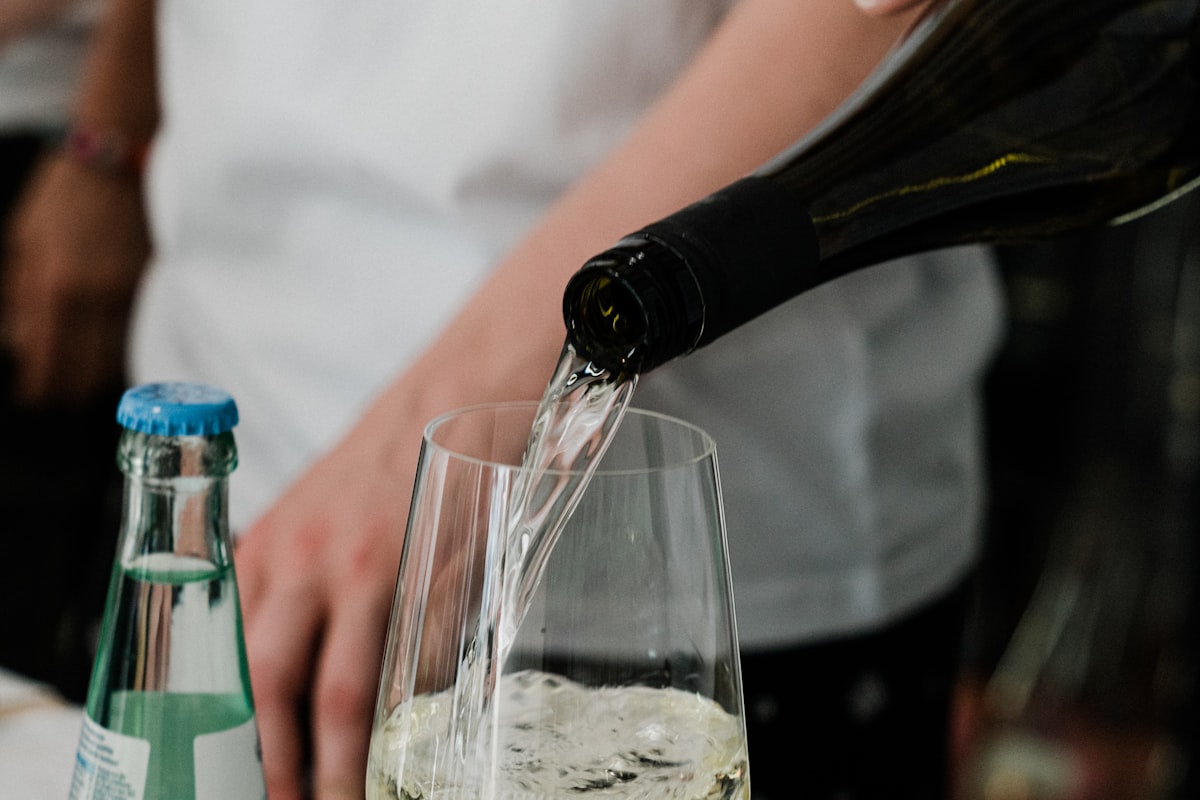 Pale gold dry white wine being poured into a glass in a kitchen setting
